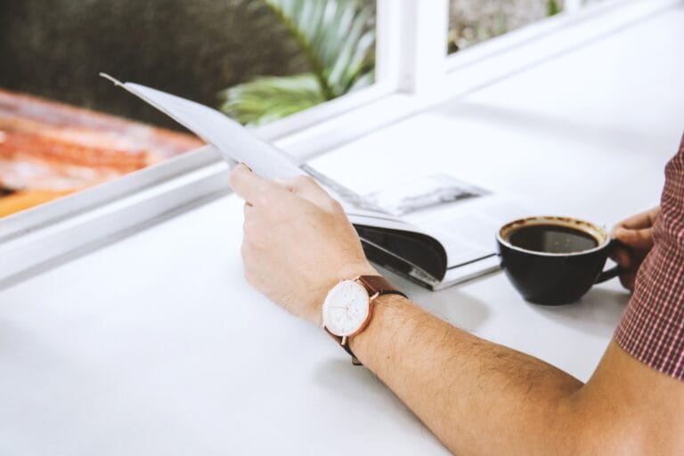 Man hand holding a magazine and a cup of coffee