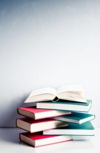 Open book on a green and red pile of books