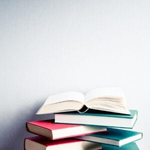 Open book on a green and red pile of books