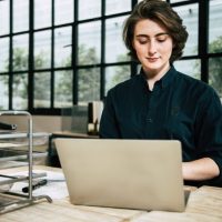 Professional woman using laptop in a stylish office environment, focused on work.