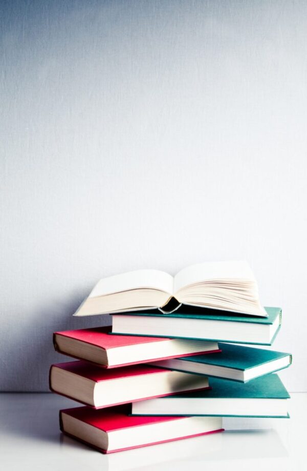 Open book on a green and red pile of books